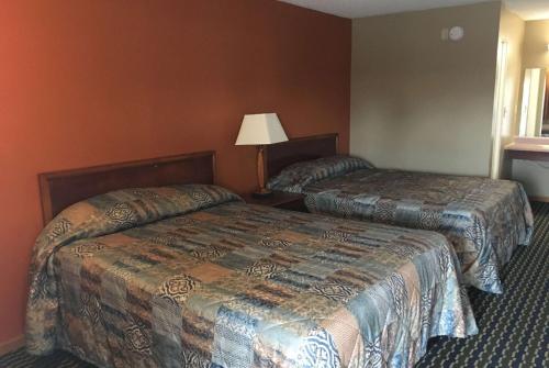 a hotel room with two beds and a lamp at Knights Inn Merrillville in Merrillville