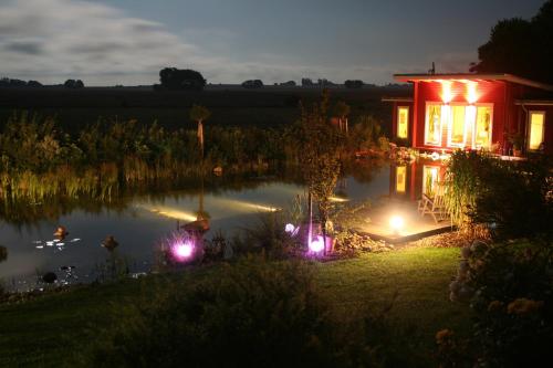a house with lights next to a pond at night at Hotel & Restaurant Zum Kap Arkona in Putgarten