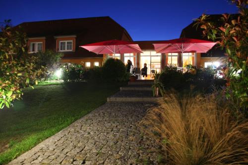 a house with two pink umbrellas in front of it at Hotel & Restaurant Zum Kap Arkona in Putgarten