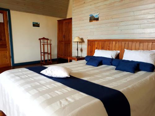 a large bed with blue and white pillows on it at Hotel le Trianon in Antsirabe
