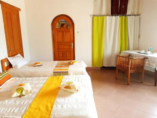 two beds in a room with a sink and a bathroom at Hotel le Trianon in Antsirabe