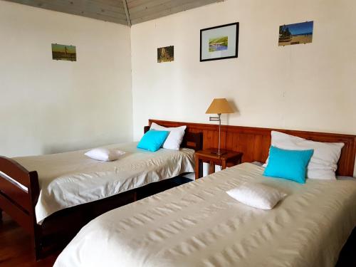 two beds in a room with blue pillows at Hotel le Trianon in Antsirabe