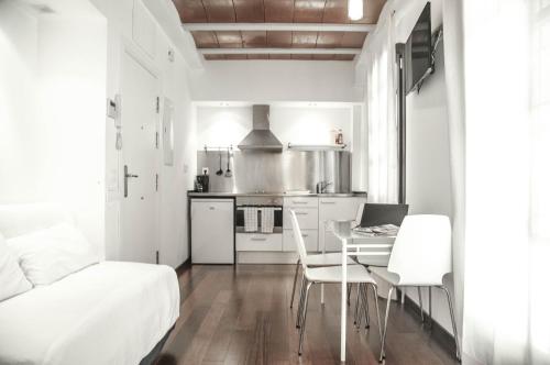 バルセロナにあるBarcelona Beach Apartmentsの白いアパートメントで、キッチン、テーブル、椅子が備わります。