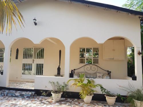 a white house with arches and potted plants at Mandinka Lodge in Kololi