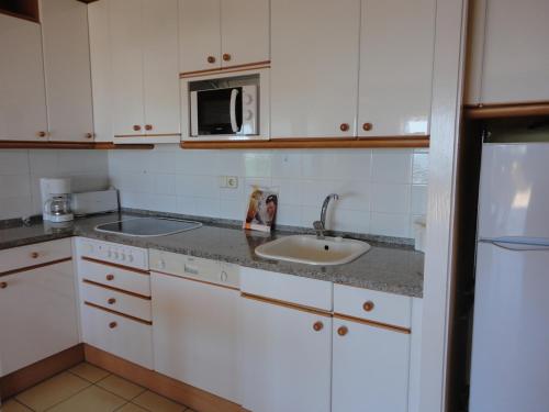 une cuisine avec un évier et un micro-ondes dans l'établissement Valentina Platja, à Sant Antoni de Calonge