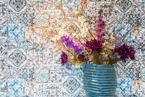 a blue vase with flowers in front of a wall at Hotel Zilt in Vlissingen