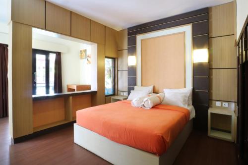 a bedroom with a bed with an orange bedspread at Kondra Premiere Guest House Kuta in Kuta