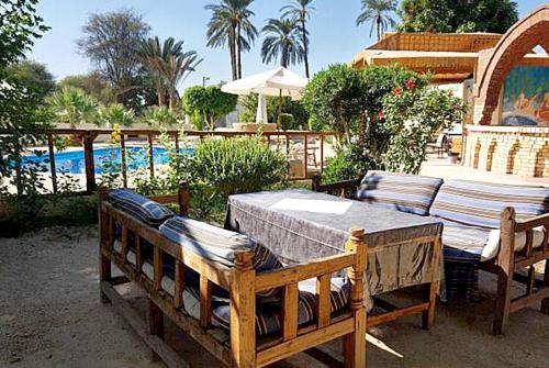 a patio with a table and chairs next to a pool at Hotel Sheherazade Luxor in Luxor