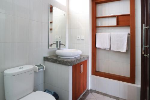 a bathroom with a white toilet and a sink at Kondra Premiere Guest House Kuta in Kuta