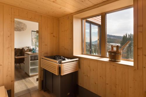 a log cabin kitchen with a stove and a window at Waldhotel Schinkenwirt in Olsberg