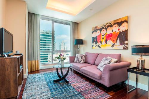 a living room with a pink couch and a tv at Sky Villas Apartments in Bangkok