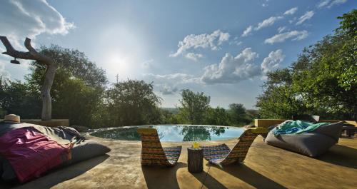 a patio with two chairs and a swimming pool at Geiger's Camp in Timbavati Game Reserve by NEWMARK in Timbavati Game Reserve