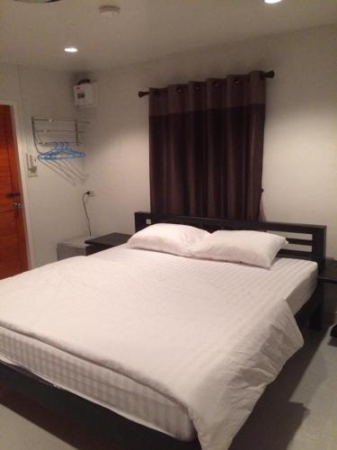 a bedroom with a large white bed with a window at Baan Phu Jad Kan in Uttaradit