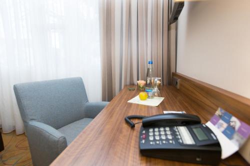 a desk with a telephone and a chair in a room at AKZENT Hotel Restaurant Altdorfer Hof in Weingarten