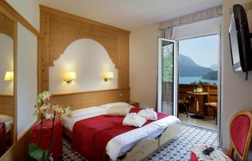 モルヴェーノにあるHotel Olympiaのベッドと大きな窓が備わるホテルルームです。