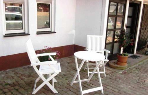Duas cadeiras brancas e uma mesa num pátio em Bauernhof Heist em Langen-Brombach