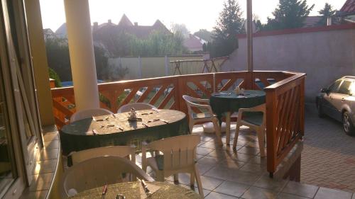 a patio with tables and chairs on a balcony at Erika Pension in Keszthely