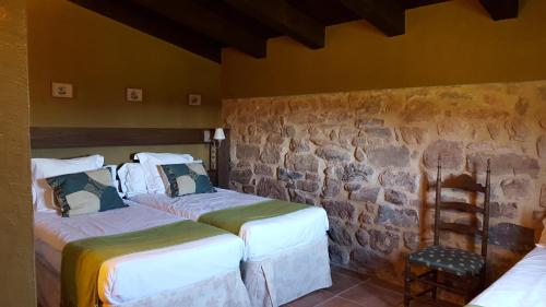 two beds in a room with a stone wall at La Torre Blanca in Cardona