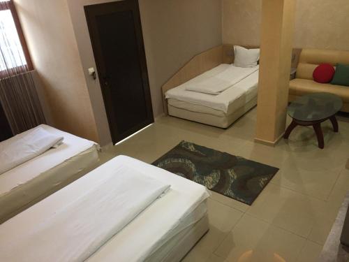a room with two beds and a couch and a table at Семеен Хотел Русалка in Svishtov
