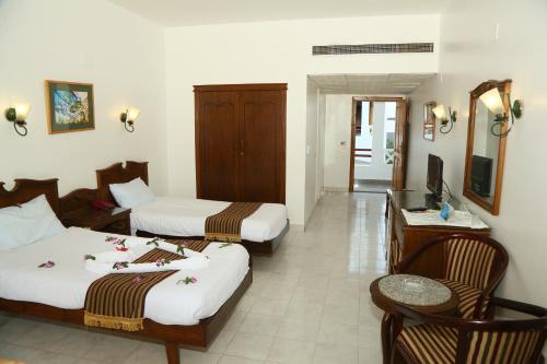 a hotel room with two beds and a desk at Happy Life Village Dahab in Dahab