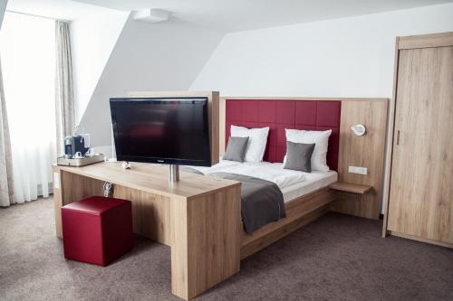 a bedroom with a bed with a desk and a tv at Hotel Specht by Trotmannia in Dortmund