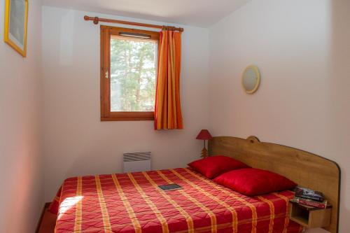 een slaapkamer met een bed met een rode deken en een raam bij Résidence Goélia Les Balcons d'Anaïs in La Norma