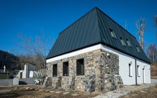 a church with a black roof and a stone building at Galyatető Turistacentrum in Galyatető