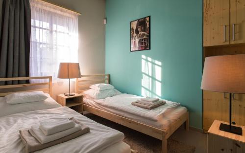 two beds in a room with blue walls and a window at Galyatető Turistacentrum in Galyatető