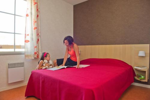 une femme et une petite fille assises sur un lit dans l'établissement Résidence Goélia Aquaresort, à Nérac