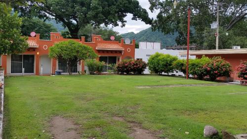 an orange and white house with a yard at Habitaciones Lucero 4 in Santa María del Oro