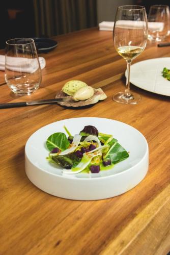 a plate of salad on a wooden table with wine glasses at Lagos Avenida Hotel in Lagos