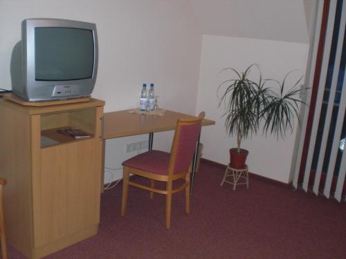 a room with a desk with a television and a chair at Landgasthof Schubbkoarn's Ruh in Fulda