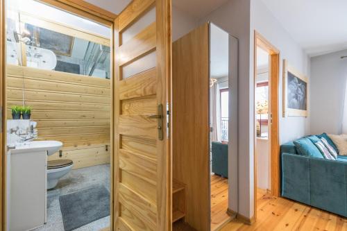 a bathroom with a wooden door with a sink and a toilet at Apartament Marmurki Zakopane in Zakopane
