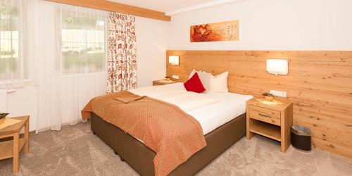 a bedroom with a large bed with white sheets and red pillows at Bachmann Appartements in Sankt Anton am Arlberg