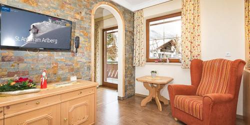 a living room with a tv on a brick wall at Bachmann Appartements in Sankt Anton am Arlberg
