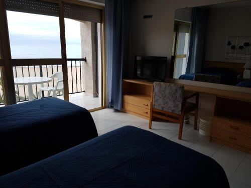 a bedroom with a bed and a television and a balcony at Hotel Neptuno in Oropesa del Mar