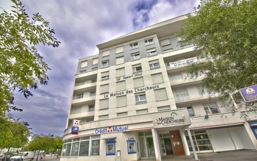 - un grand bâtiment blanc dans une rue de la ville dans l'établissement KOSY Appart'Hôtels - La Maison Des Chercheurs, à Vandœuvre-lès-Nancy