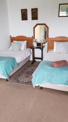a bedroom with two beds and a table with a mirror at Knysna Manor House in Knysna