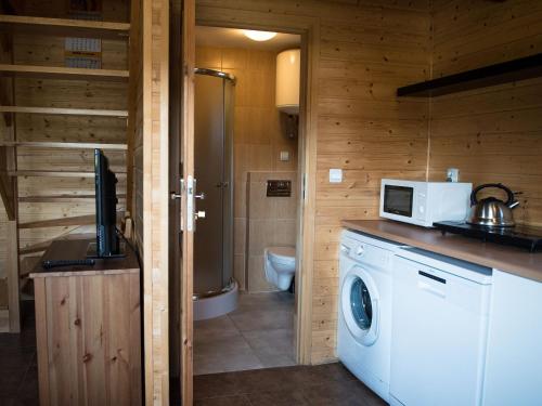 a kitchen with a washing machine and a microwave at Domki letniskowe w Kopalinie in Kopalino