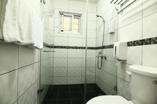 a bathroom with a shower with a toilet and a window at Home Sweet Beach Hotel in Xiaoliuqiu