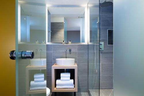 a bathroom with two sinks and a glass shower at ibis Styles Bourg La Reine in Bourg-la-Reine