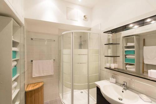 une salle de bain blanche avec une douche et un lavabo dans l'établissement Appartement carre d'or, à Nice
