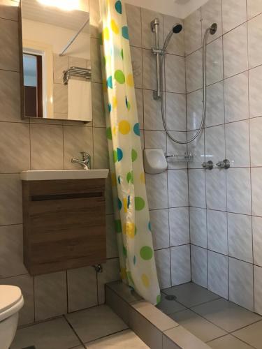 e bagno con tenda per la doccia, servizi igienici e lavandino. di Hotel Anthousa a Samos