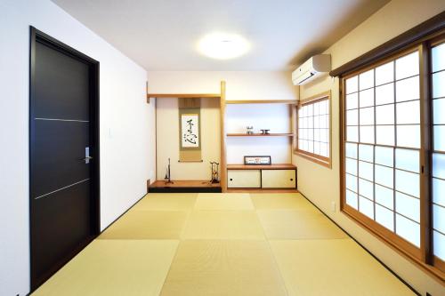 an empty hallway with a black door and windows at Tsumugi Inn in Kyoto