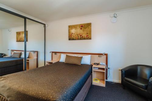 a hotel room with a bed and a chair at Canning Bridge Auto Lodge in Perth