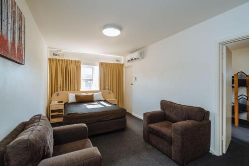 a hotel room with a bed and a couch and chairs at Canning Bridge Auto Lodge in Perth