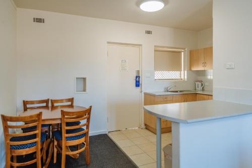 a kitchen with a table and chairs and a counter at Canning Bridge Auto Lodge in Perth