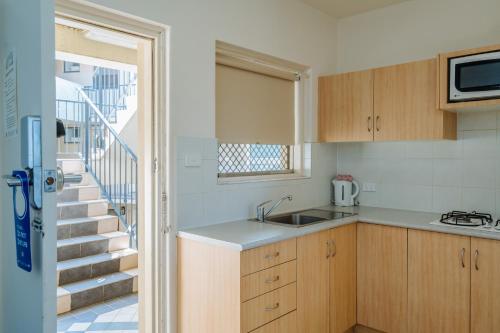 a kitchen with a sink and a stairway at Canning Bridge Auto Lodge in Perth