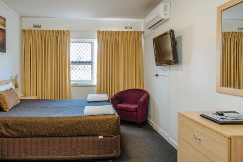 a bedroom with a bed and a chair and a television at Canning Bridge Auto Lodge in Perth