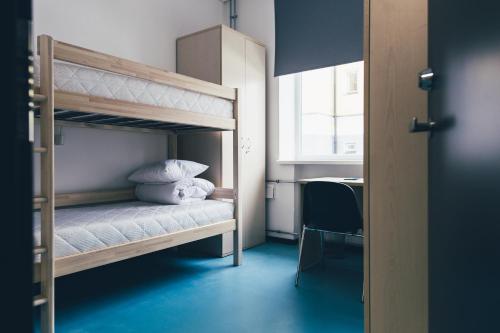 een slaapkamer met een stapelbed met witte lakens en kussens bij Ülemiste Airport Hostel in Tallinn